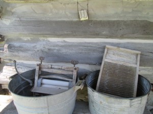 The wash tub with scrub board and the rinse tub with wringer set on the porch ready for use.