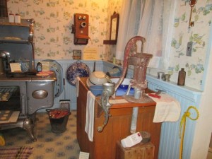 This is the kitchen of a farm house a 100 years ago. After an elderly woman passed away her family donated all the furnishes to be set up in rooms just like in the house. Voice buttons with the son of this owners describes what it was like to sit in the cozy kitchen on cold winter days, warming up in between doing chores.